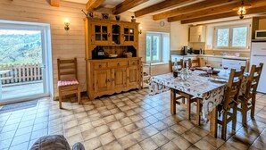 Ein Holzinterieur mit Esstisch, Stühlen, Küchenzeile und Blick durch eine Tür.