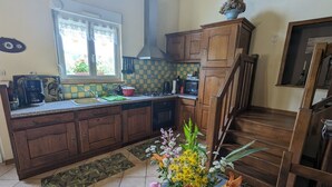 Une cuisine avec des meubles de rangement en bois, une cuisinière et une fenêtre ornée de rideaux en dentelle.