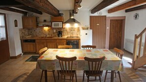 A cozy kitchen with wooden cabinets, a dining table with chairs, and a refrigerator.
