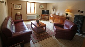 A living room with a sofa, armchair, coffee table, TV, and a cabinet.