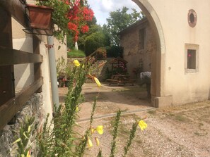Une cour extérieure agrémentée d’un mur de pierre rustique, d’un banc en bois et d’une petite structure en bois.