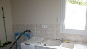 Een kleine keuken met een spoelbak, een groene dweil en een rode stofzuiger.