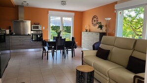 Een moderne woonkamer met een bank, eettafel en keukenhoek.