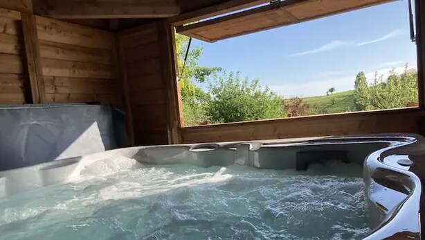 Een houten hut met een jacuzzi en uitzicht op begroeiing.