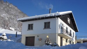 Un bâtiment à deux étages, avec un toit enneigé et un balcon.