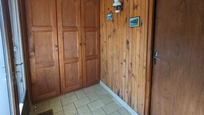 Un couloir avec des lambris en bois, une porte et deux petits cadres représentant des tableaux accrochés au mur.