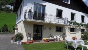 Une maison à deux étages avec un balcon, une antenne parabolique et un espace salon extérieur.
