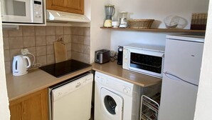 A compact kitchen with a microwave, toaster, kettle, dishwasher, and refrigerator. - T2 Apartment with balcony, equipped kitchen, parking (Les Angles)