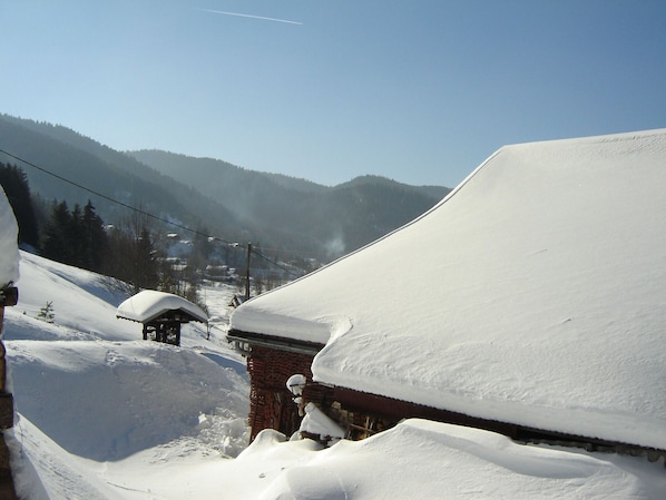 Un village de montagne enneigé, avec des bâtiments traditionnels et un ciel dégagé.