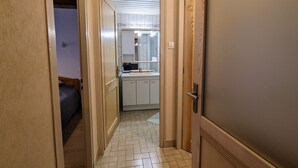 A narrow hallway leading to a kitchen with white cabinets and a tiled floor. - Charming Mountain Cottage with Ski Access, WiFi, and Family Amenities in La Bresse (La Bresse)