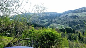 A table and chair set on a grassy hill overlooking a valley with scattered houses and dense forest. - Charming studio in farmhouse with terrace and parking - Vosges mountains (Le Menil)