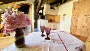 A wooden table with a white tablecloth, a vase of pink flowers, and two wine glasses. - Charming studio in farmhouse with terrace and parking - Vosges mountains (Le Menil)