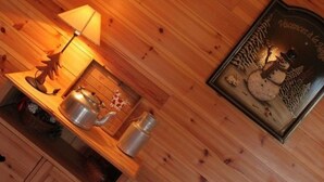 Un mur en bois orné d’un tableau encadré représentant un bonhomme de neige et d’une lampe posée sur une étagère.