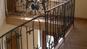 A wooden staircase with a wrought iron railing and a chandelier.