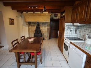 Een keuken met een houten tafel, stoelen, een fornuis en een vaatwasser.