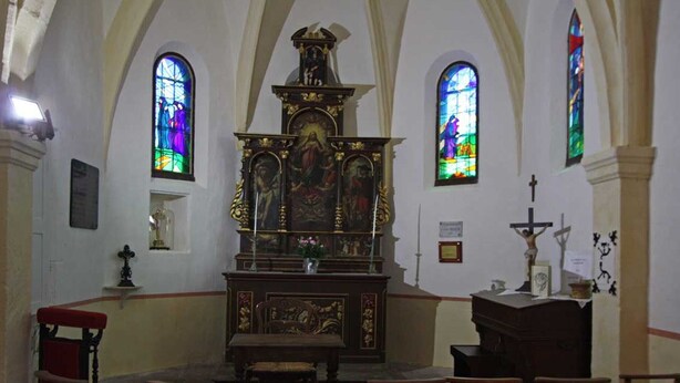 Interior de iglesia con altar central, bancos y vidrieras.