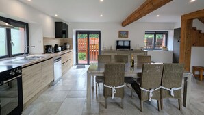 Een moderne keuken met een eethoek, voorzien van een groot schiereiland, inbouwapparatuur en een televisie.