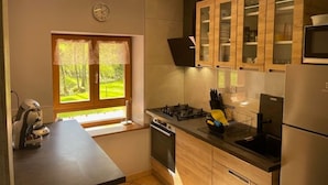 Een moderne keuken met houten kastjes, een inbouwmagnetron en een raam met uitzicht op groen.