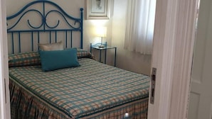 A bedroom with a bed, a bedside table, a lamp, and a framed picture on the wall.