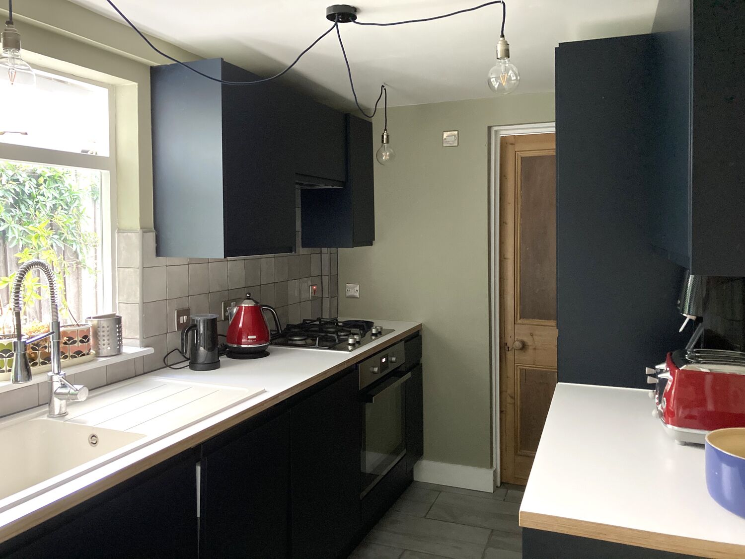 A modern kitchen with black cabinets, a gas stove, a kettle, and a coffee maker.