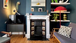 A living room with a fireplace, a television, a sofa, and a bookshelf. - Lilly Cottage - Fisherman's Cottage Whitstable (Whitstable)