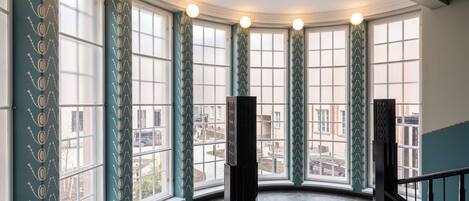 A corner room with large windows, a staircase, and a view of the city.