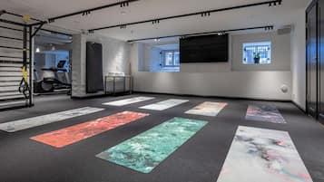 Une salle de sport moderne équipée de matériel d’exercice, de tapis de yoga et dotée d’une grande fenêtre.