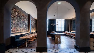 Un restaurante espacioso con techos altos, columnas en arco y un gran mural en la pared.