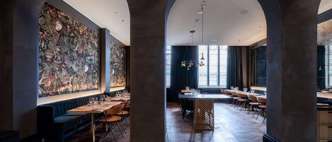 Un restaurante espacioso con techos altos, columnas en arco y un gran mural en la pared.