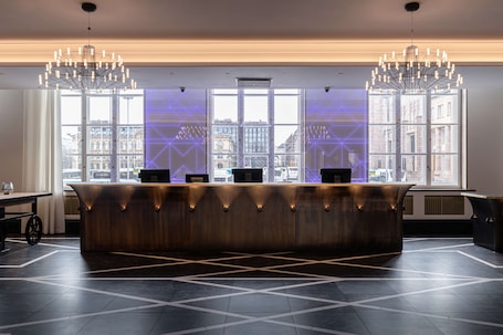 A modern reception area with a wooden reception desk, large windows, and a geometric floor pattern.