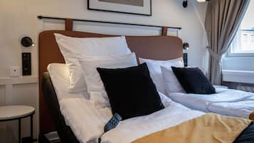 A hotel room with a bed, bedside table, lamp, and a framed picture on the wall.