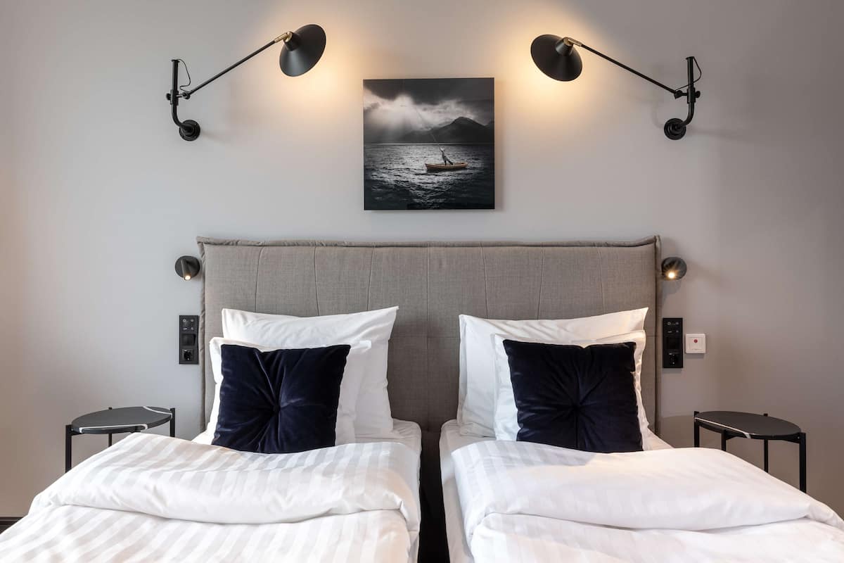 A double bed with a grey headboard, two bedside tables, and a wall-mounted picture of a boat on water.