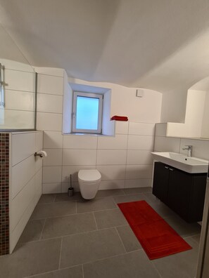Une salle de bain avec des toilettes, un lavabo et une fenêtre.