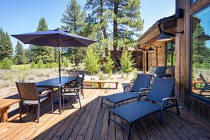 Une terrasse en bois aménagée avec du mobilier d’extérieur, notamment une table, des chaises et un parasol.