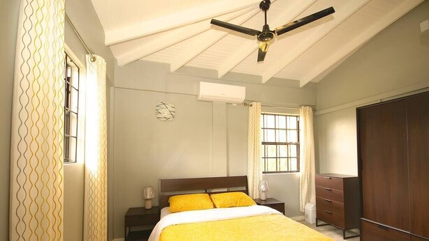 A bedroom with a bed, a wardrobe, a nightstand, and a ceiling fan. - Veronica's - Breathe Easy - Reduit Apartment #1 (Rodney Bay)