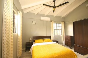A bedroom with a bed, a wardrobe, a nightstand, and a ceiling fan. - Veronica's - Breathe Easy - Reduit Apartment #1 (Rodney Bay)