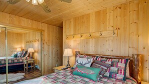Un dormitorio con paneles de madera, una cama, mesitas de noche, lámparas y un espejo.