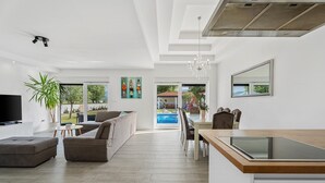 A modern living room with a TV, sofa, and dining area.