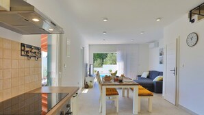 A modern kitchen with a dining area, a sofa, and a clock on the wall. - Seaview Villa Lemaro, a 2-bedroom villa with a 28 sqm private pool in Krilo Jesenice (Jesenice)