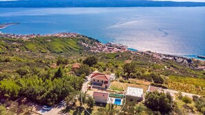 An aerial view of a coastal area with a small village, green hills, and a large body of water. - Seaview Villa Lemaro, a 2-bedroom villa with a 28 sqm private pool in Krilo Jesenice (Jesenice)
