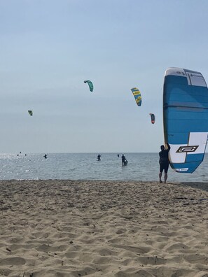 A beach with people windsurfing and a large blue kite. - Salvo Sandbox: Ocean-Side, Dog-Friendly Cottage (Salvo)