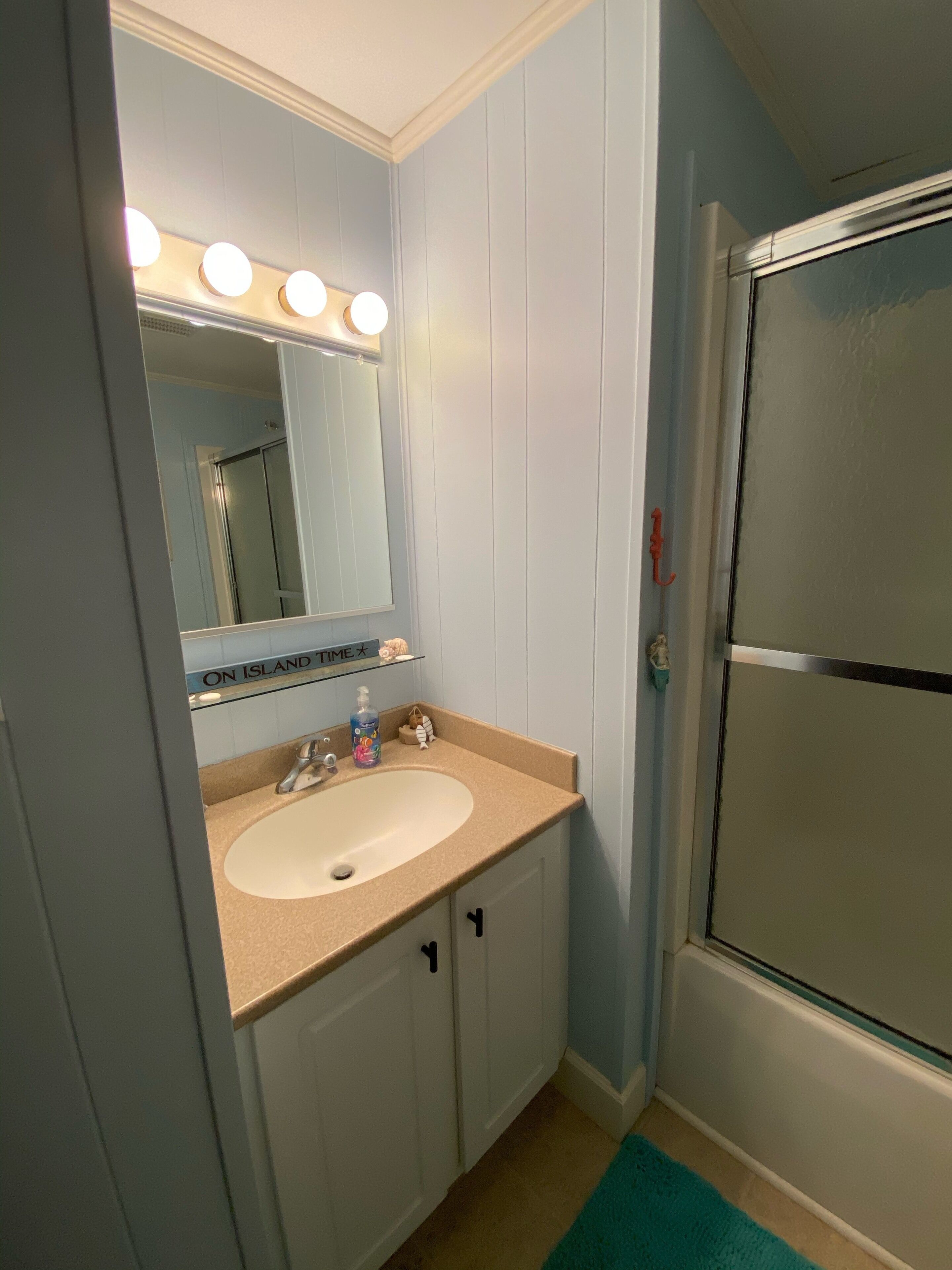 A bathroom with a sink, mirror, and shower.