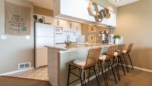 A modern kitchen with a central island, white cabinetry, and a hanging plant.
