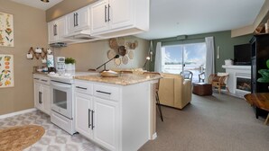 A modern kitchen with white cabinetry, a central island, and a dining area with a sofa and chairs.