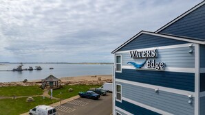 A building with a sign reading "WATERS Edge" overlooking a beach and water.