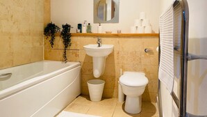 Een moderne badkamer met een bad, wastafel en toilet.