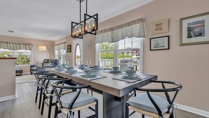 A dining area with a long table, chairs, and a chandelier.