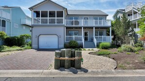 A two-story residential building with a front garage, a balcony on the second floor, and a landscaped front yard.