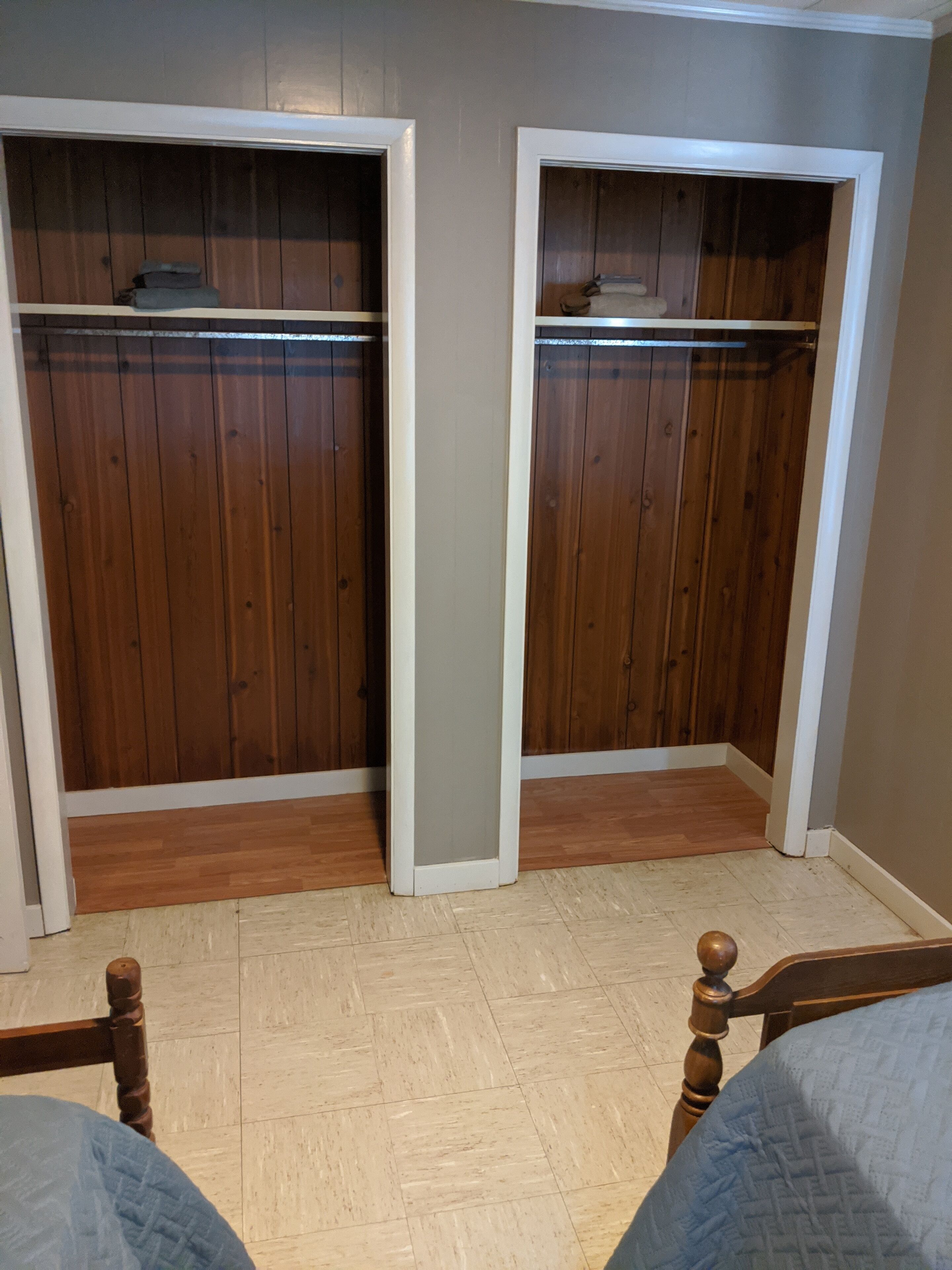 Una habitación con dos armarios de madera, suelo de madera y una cama con cubrecama azul.