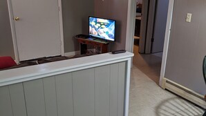 A living room with a television on a stand, a door with a small window, and a wall-mounted deer head. - Clean, full kitchen, stand alone cabin adjoining Lake Barkley State Park (Cadiz)